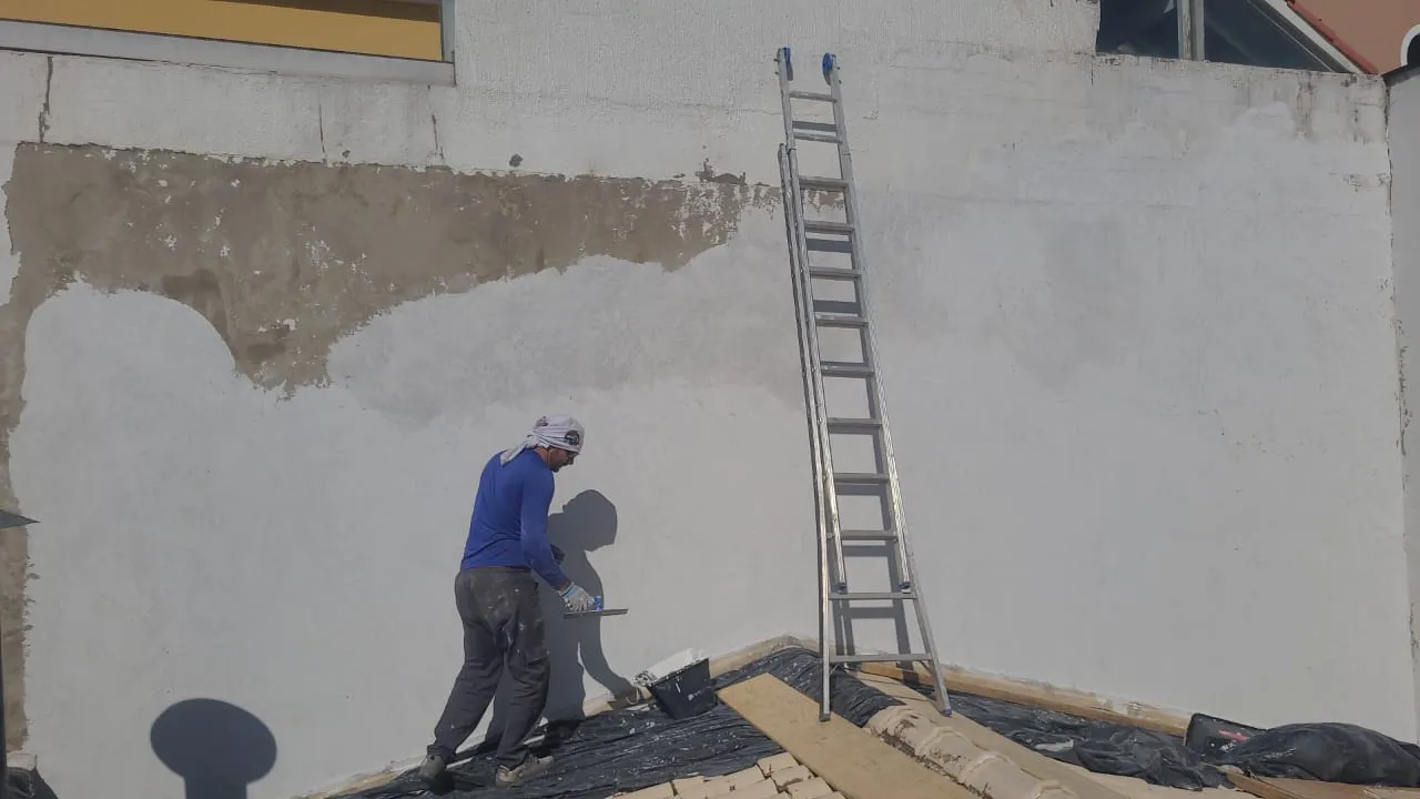 Profissional preparando um muro externo para impermeabilização e pintura.